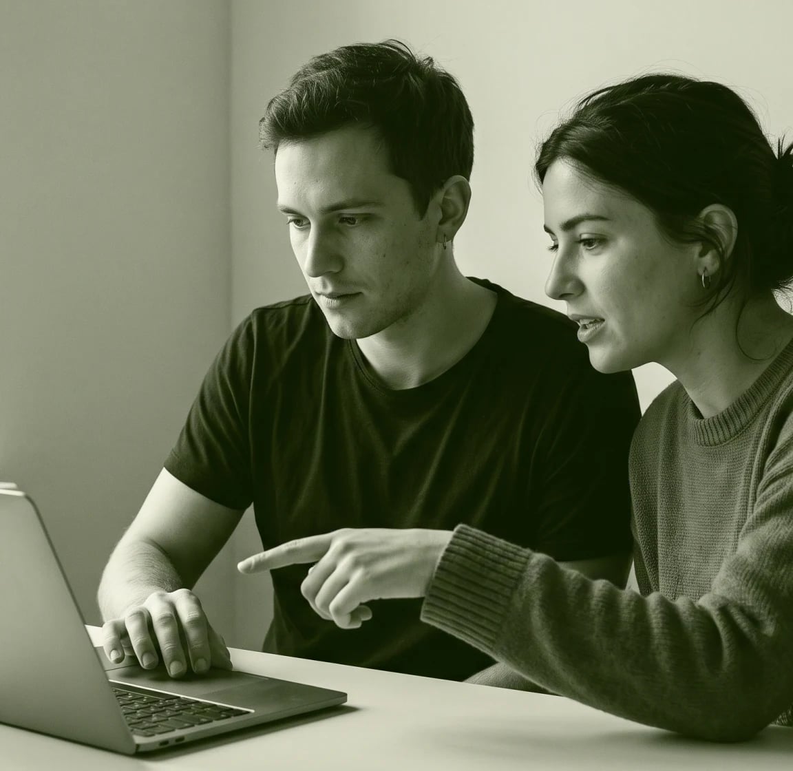 Two people at a laptop, one pointing at the screen, in green duotone