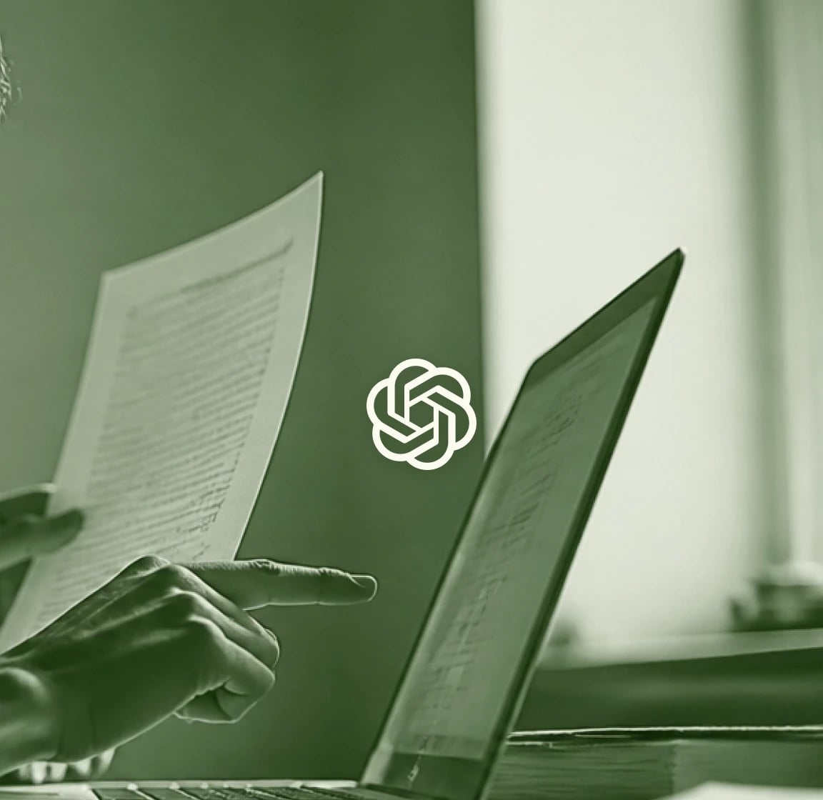 Person reading a printed page in front of a laptop